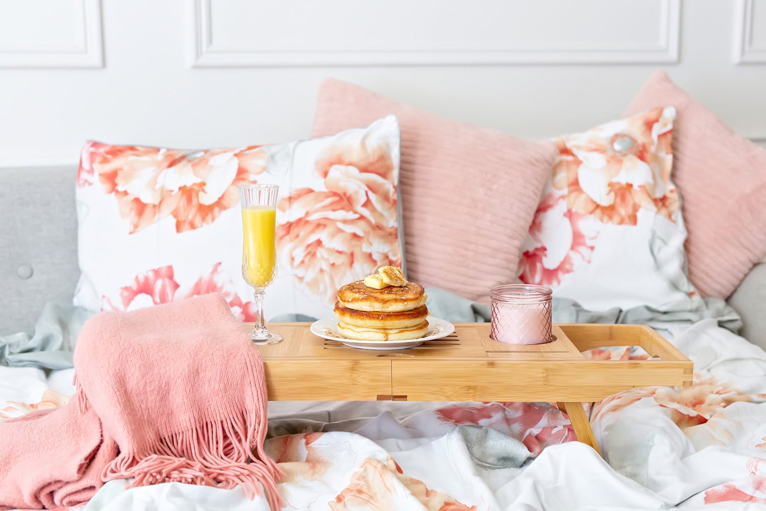 Fancy breakfast in bed with fluffy pancakes, milk and orange juice on a wooden tray
